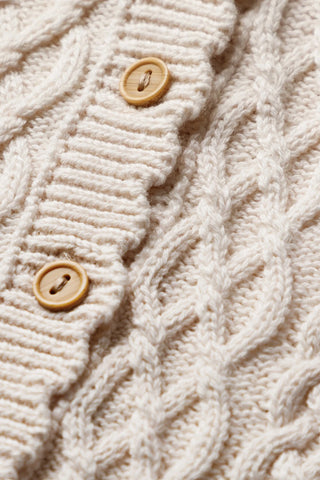 Close up of luxury cable knit baby romper showing wooden buttons